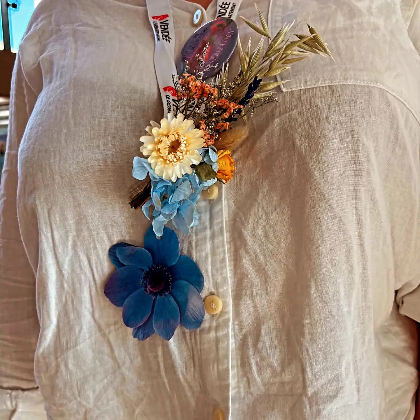 Boutonnière en fleurs séchées : anémone bleue, immortelles et graminées.