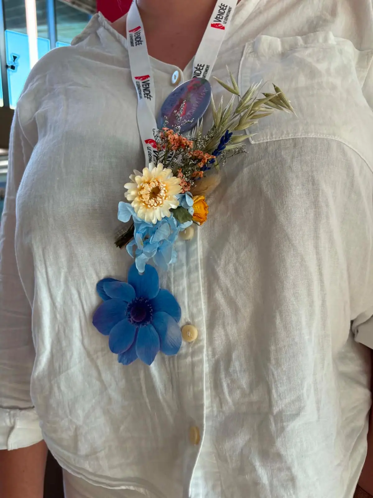 Boutonnière fleurie portée sur une chemise en lin.