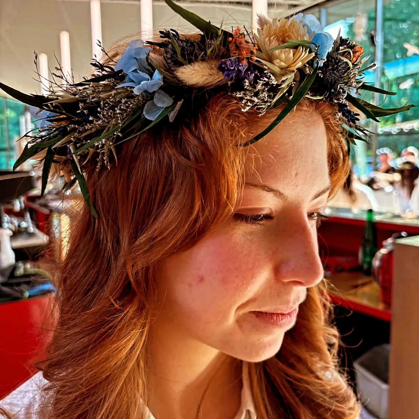 Couronne de fleurs séchées aux chardons bleus et graminées, portée.