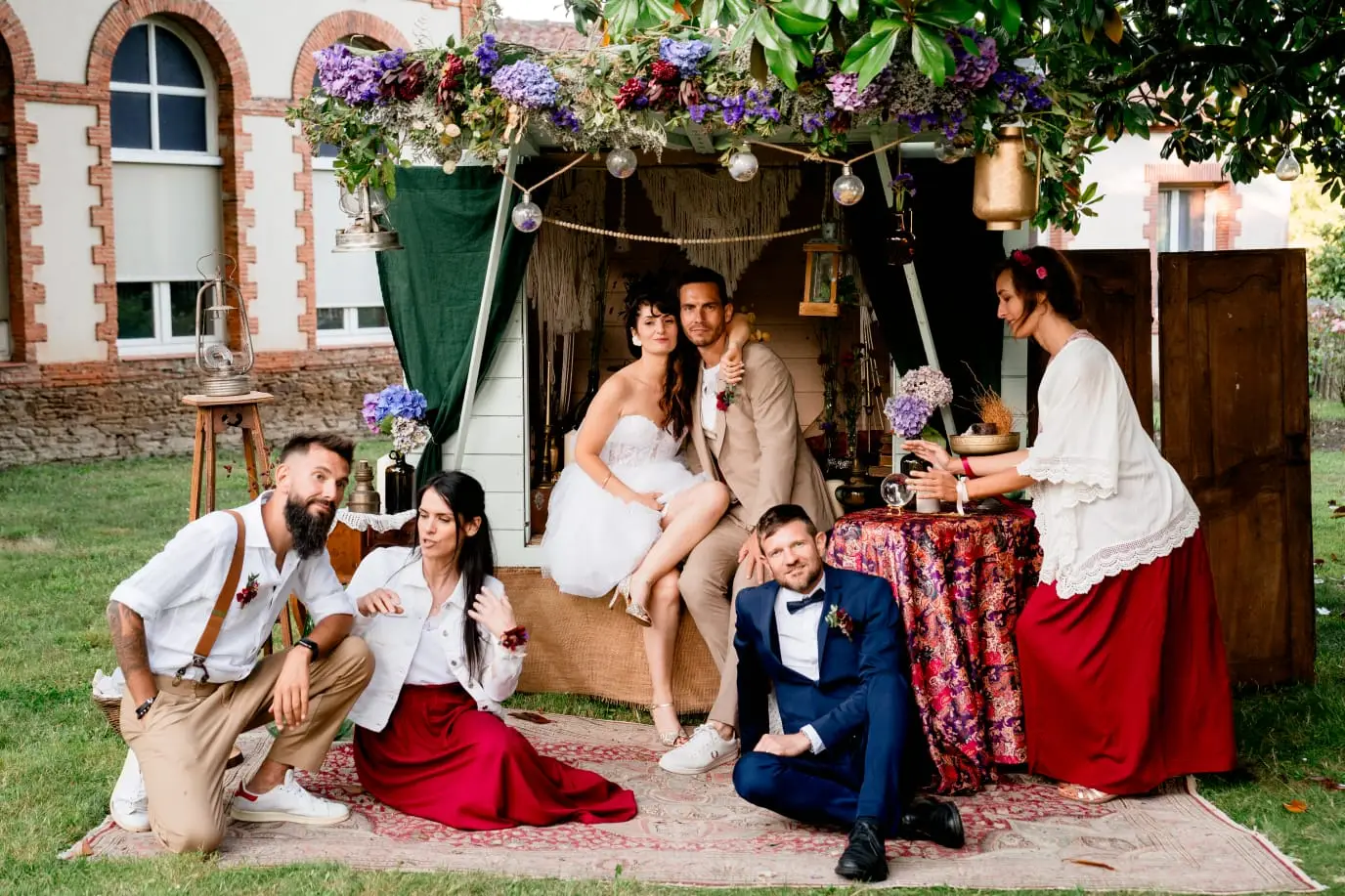 Les mariés et leurs proches posent devant la cabane fleurie.